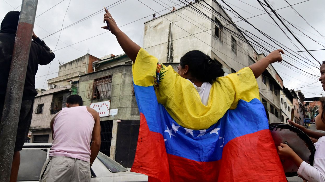 A woman wears a Venezuela flag as other resident bangs a pot to protest against the election results after both President Nicolas Maduro and his opposition rival Edmundo Gonzalez claimed victory in Sunday's presidential election at Los Magallanes de Catia neighborhood, in Caracas, Venezuela July 29, 2024.