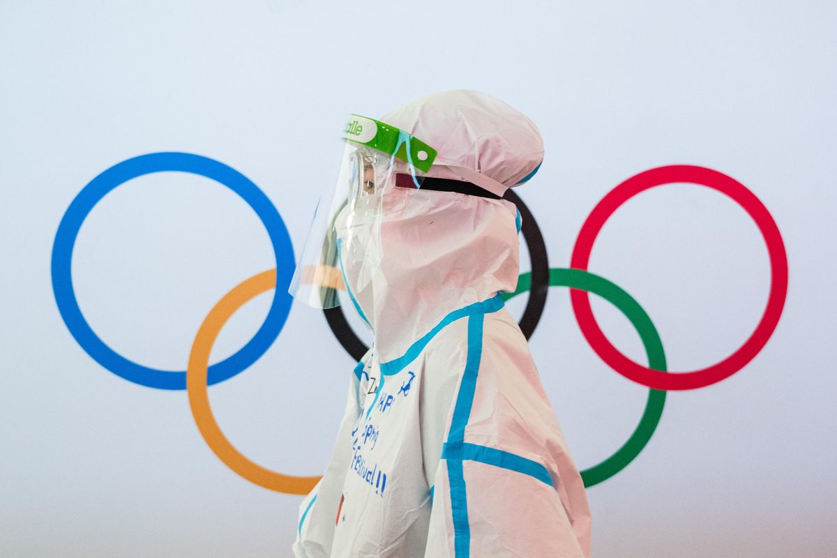 A worker in full-body personal protective equipment at Beijing Capital International Airport walks past the Olympic rings ahead of the 2022 Winter Olympics on February 1, 2022 in Beijing.