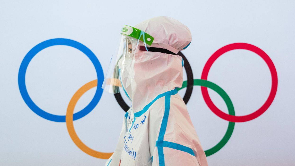 A worker in full-body personal protective equipment at Beijing Capital International Airport walks past the Olympic rings ahead of the 2022 Winter Olympics on February 1, 2022 in Beijing.