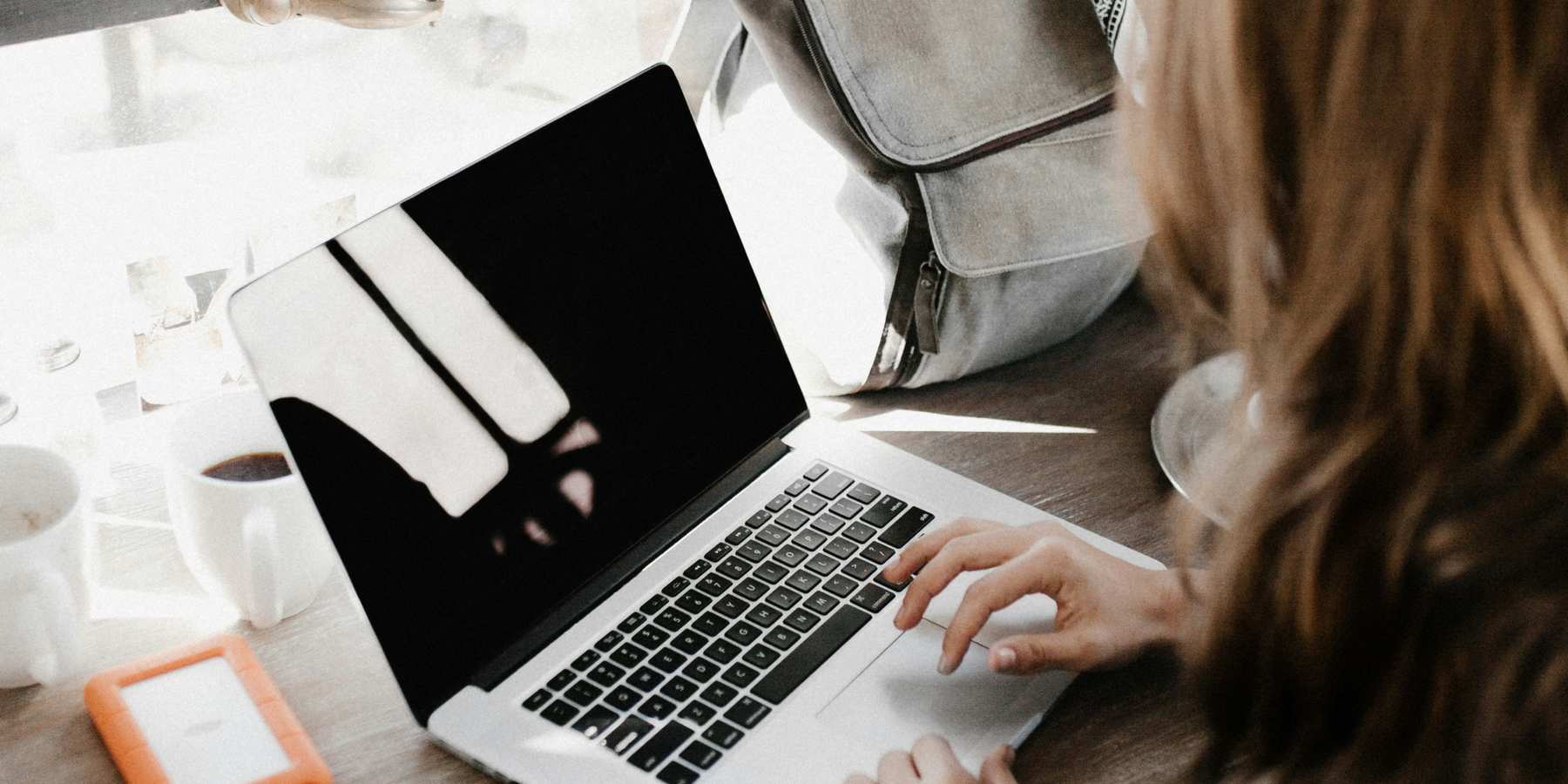 A young anonymous woman working on a laptop.