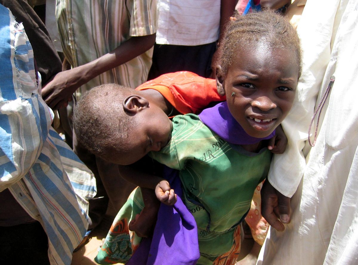 A young Darfuri girl carries her sleeping brother at Zam Zam camp in Sudan's North Darfur state