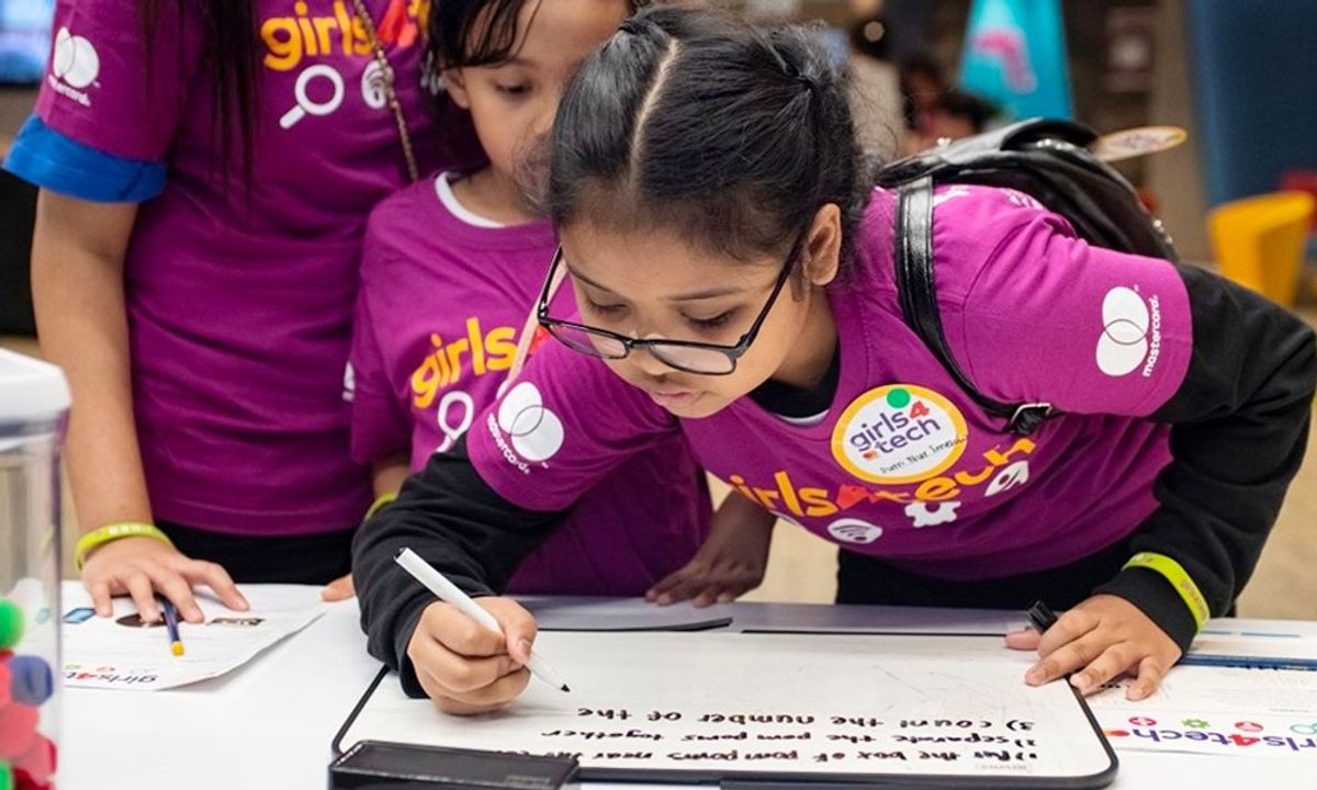 A young girl writing on a small whiteboard
