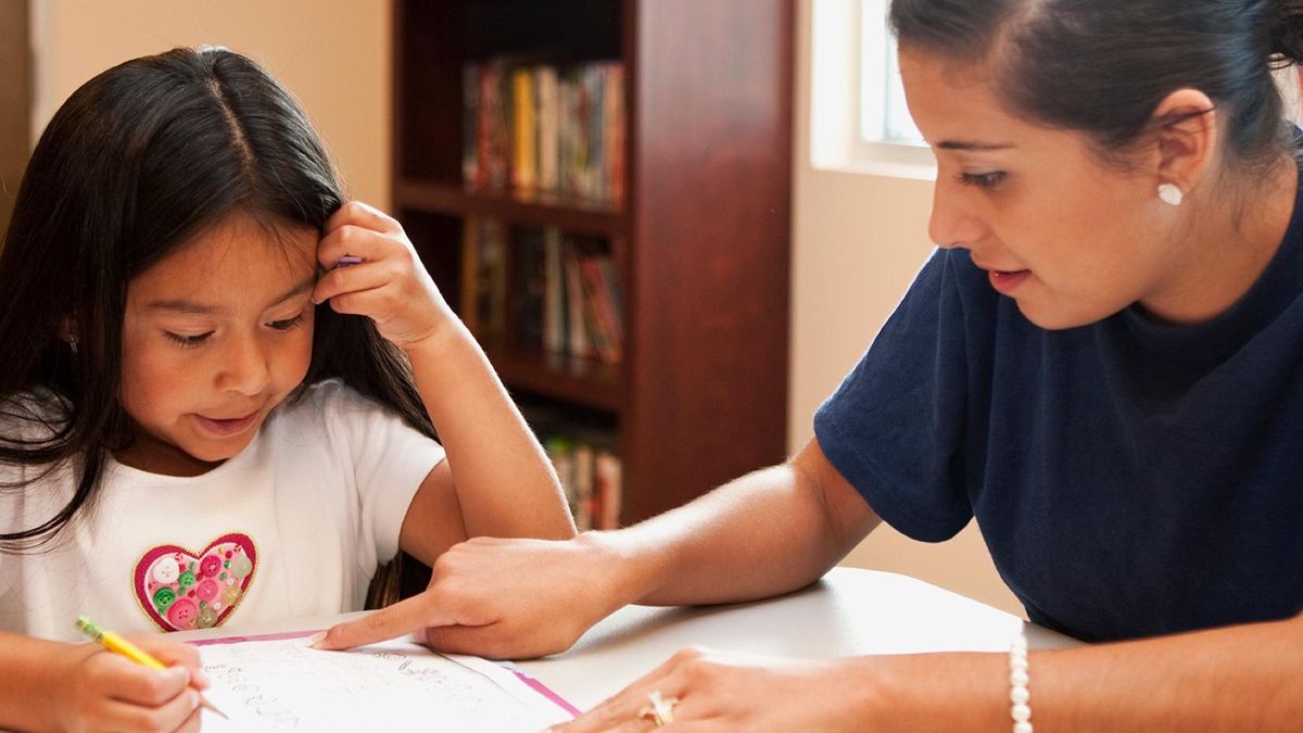 A young student gets help from a teacher. Critical support for teachers.
