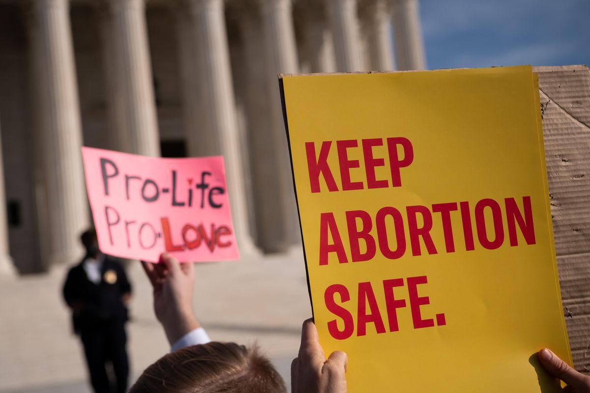 Abortion rights and anti-abortion demonstrators hold signs outside the U.S. Supreme Court while the court holds a hearing on a Mississippi abortion ban, in Washington, D.C., on Wednesday, December 1, 2021. 