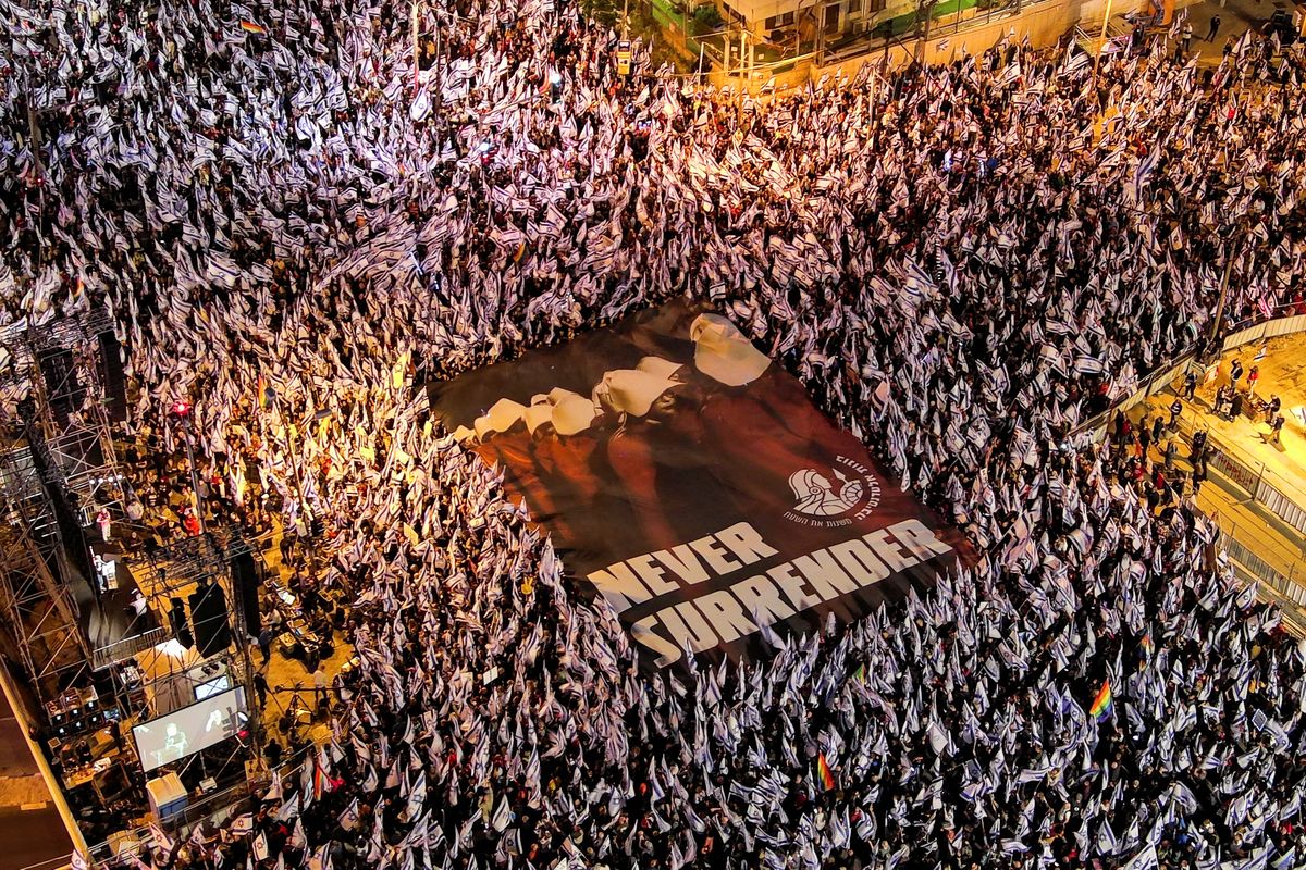 An aerial view shows protesters holding a sign depicting handmaidens from "The Handmaid's Tale" with the words "Never Surrender" as they demonstrate against Israeli PM Benjamin Netanyahu's judicial overhaul in Tel Aviv.