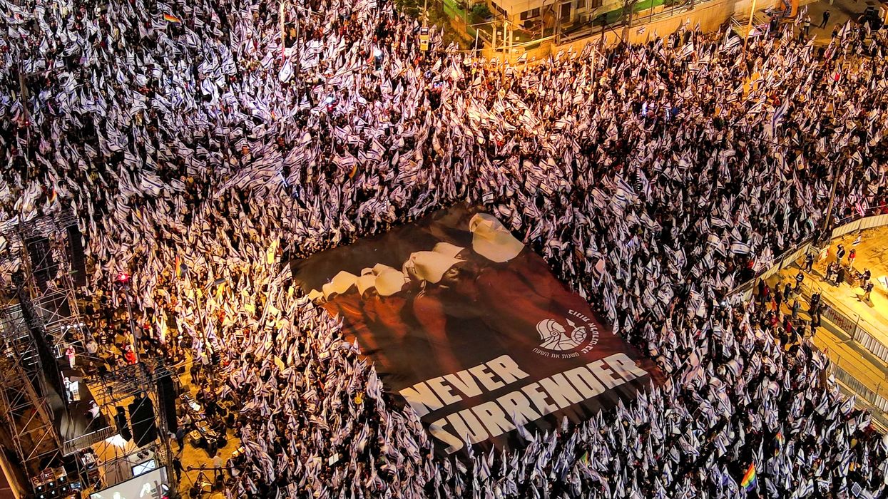 An aerial view shows protesters holding a sign depicting handmaidens from "The Handmaid's Tale" with the words "Never Surrender" as they demonstrate against Israeli PM Benjamin Netanyahu's judicial overhaul in Tel Aviv.