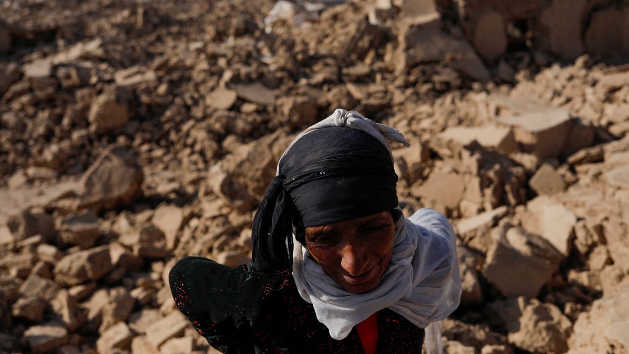 An Afghan woman stands next to her house after a recent earthquake in Chahak village in the Enjil district of Herat province, Afghanistan. Three deadly quakes have plagued the region this month.