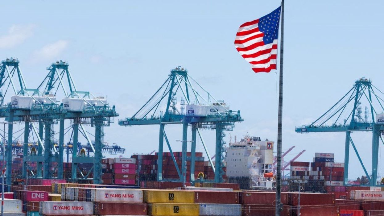 An American flag flutters over a ship and shipping containers at the Port of Los Angeles, in San Pedro California, U.S., May 13, 2025.
