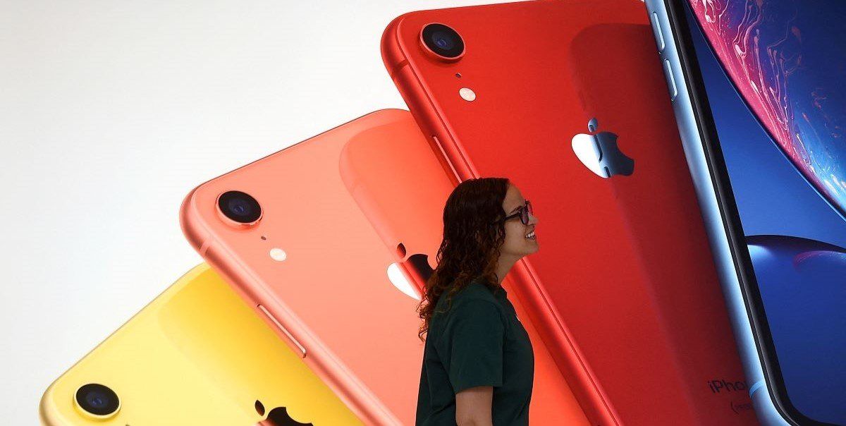 ​An Apple Store employee walks past an illustration of iPhones at the new Apple Carnegie Library during the grand opening and media preview in Washington, U.S., May 9, 2019.
