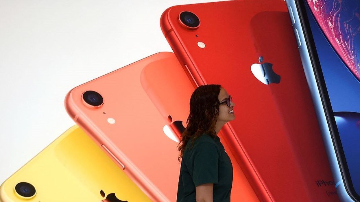 An Apple Store employee walks past an illustration of iPhones at the new Apple Carnegie Library during the grand opening and media preview in Washington, U.S., May 9, 2019.