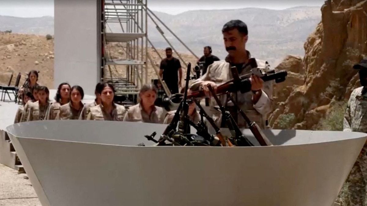 An armed PKK fighter places a weapon to be burnt during a disarming ceremony in Sulaimaniya, Iraq, July 11, 2025, in this screengrab obtained from a handout video. 