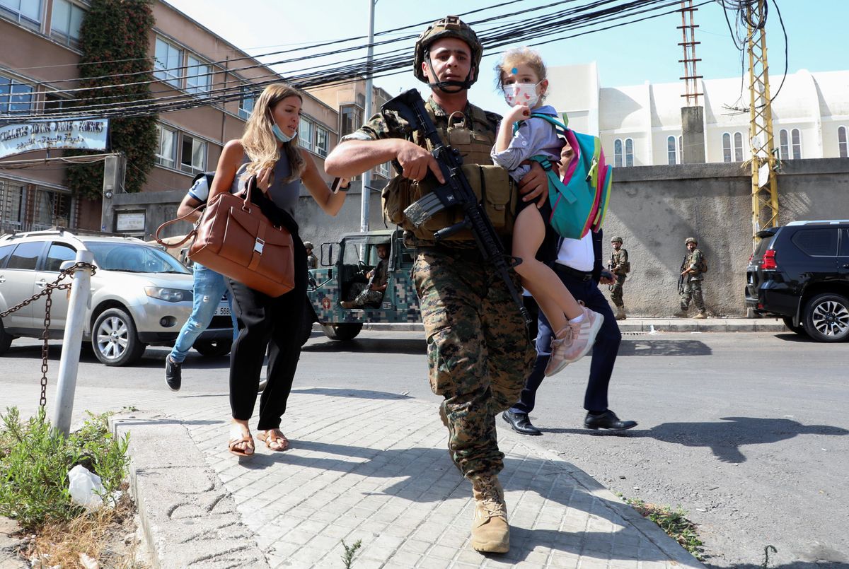 An army soldier carries a schoolchild as civilians flee after gunfire erupted at a site near a protest that was getting underway against Judge Tarek Bitar, who is investigating last year's port explosion, in Beirut, Lebanon October 14, 2021.
