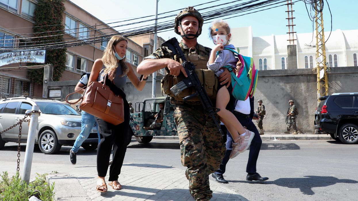 An army soldier carries a schoolchild as civilians flee after gunfire erupted at a site near a protest that was getting underway against Judge Tarek Bitar, who is investigating last year's port explosion, in Beirut, Lebanon October 14, 2021.
