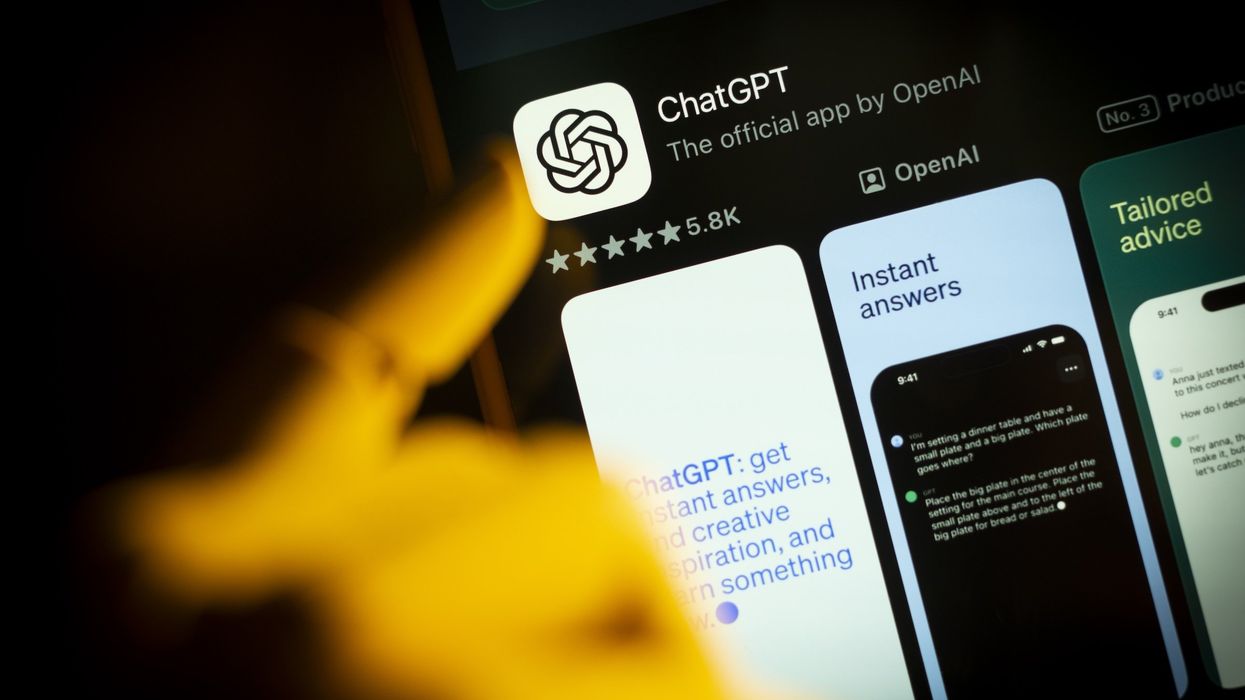 An artificial hand is seen pointing a finger at a mobile phone screen displaying the Apple App Store with the Chat GPT app in this photo illustration.