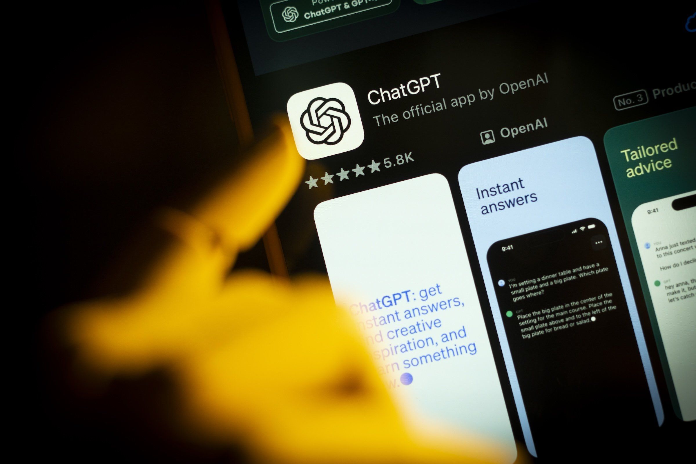 An artificial hand is seen pointing a finger at a mobile phone screen displaying the Apple App Store with the Chat GPT app in this photo illustration.