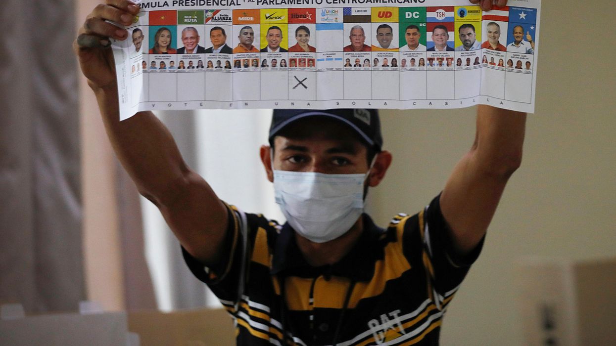 An election volunteer displays the ballot as vote counting begins during the general election, at a school in Catacamas, Honduras, November 28, 2021.