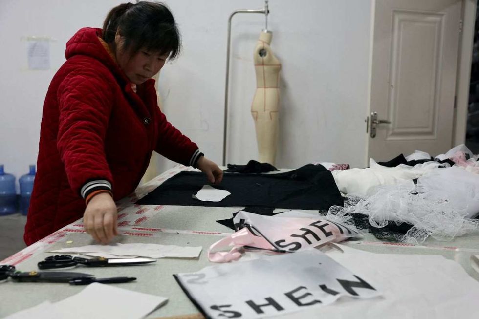 ​An employee prepares to cut a fabric next to Shein packaging at the Midnight Charm Garment lingerie factory in Guanyun county of Lianyungang, Jiangsu province, China November 25, 2024. 