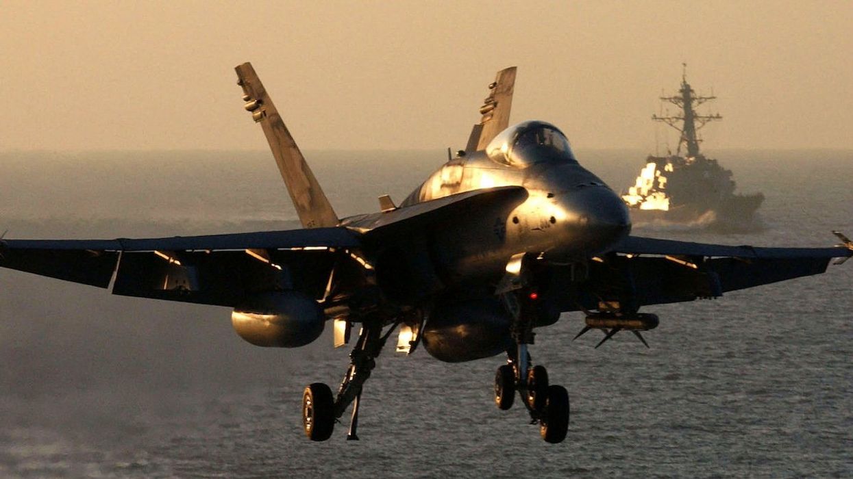 An F/A-18 Hornet approaches the flight deck of aircraft carrier USS Theodore Roosevelt as USS McFaul trails behind, October 30, 2001. Theodore Roosevelt and its carrier airwing are conducting missions in support of operation Enduring Freedom.