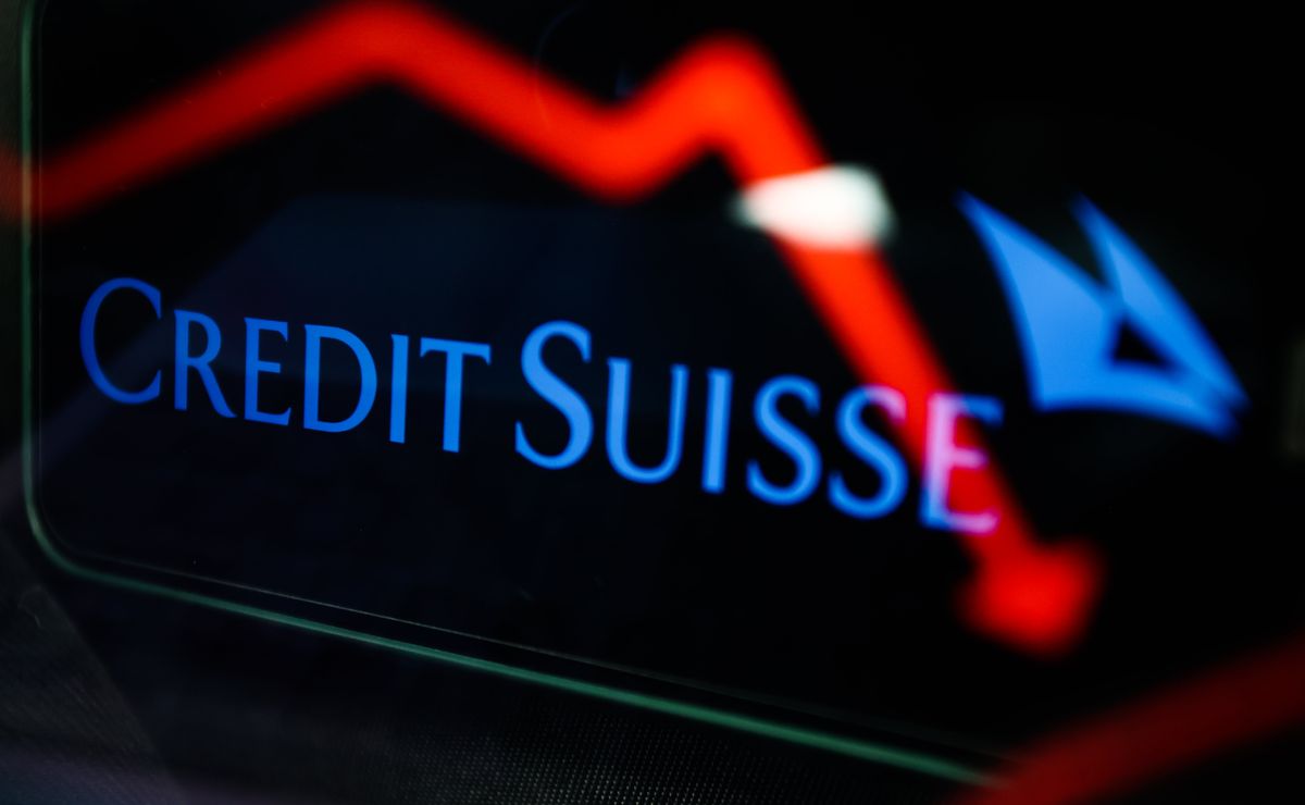 An illustrative stock chart and Credit Suisse logo displayed on a phone screen.
