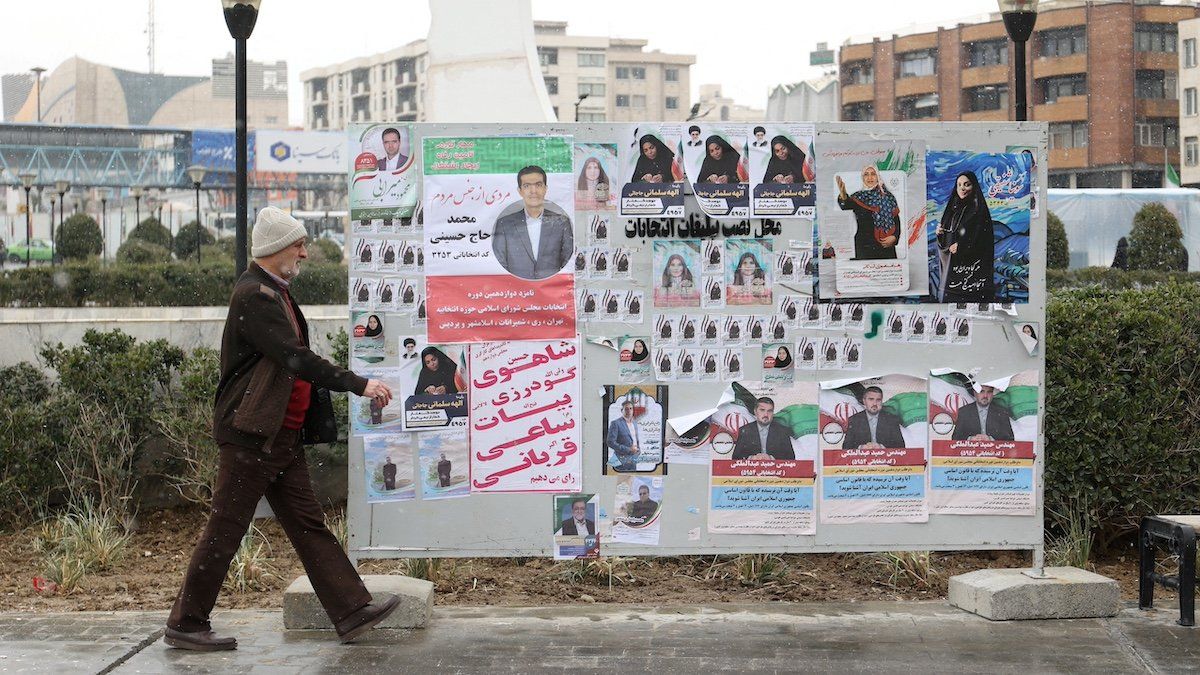 ​An Iranian man walks past campaign posters for the parliamentary election in Tehran, Iran, February 27, 2024. 