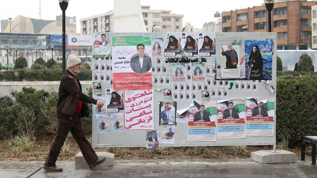 An Iranian man walks past campaign posters for the parliamentary election in Tehran, Iran, February 27, 2024.