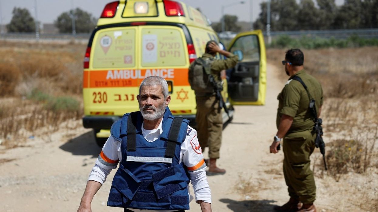 An Israeli medic walks near soldiers and an ambulance after Hamas claimed responsibility for an attack on the Kerem Shalom crossing near Israel's border with Gaza in southern Israel, on May 5, 2024.