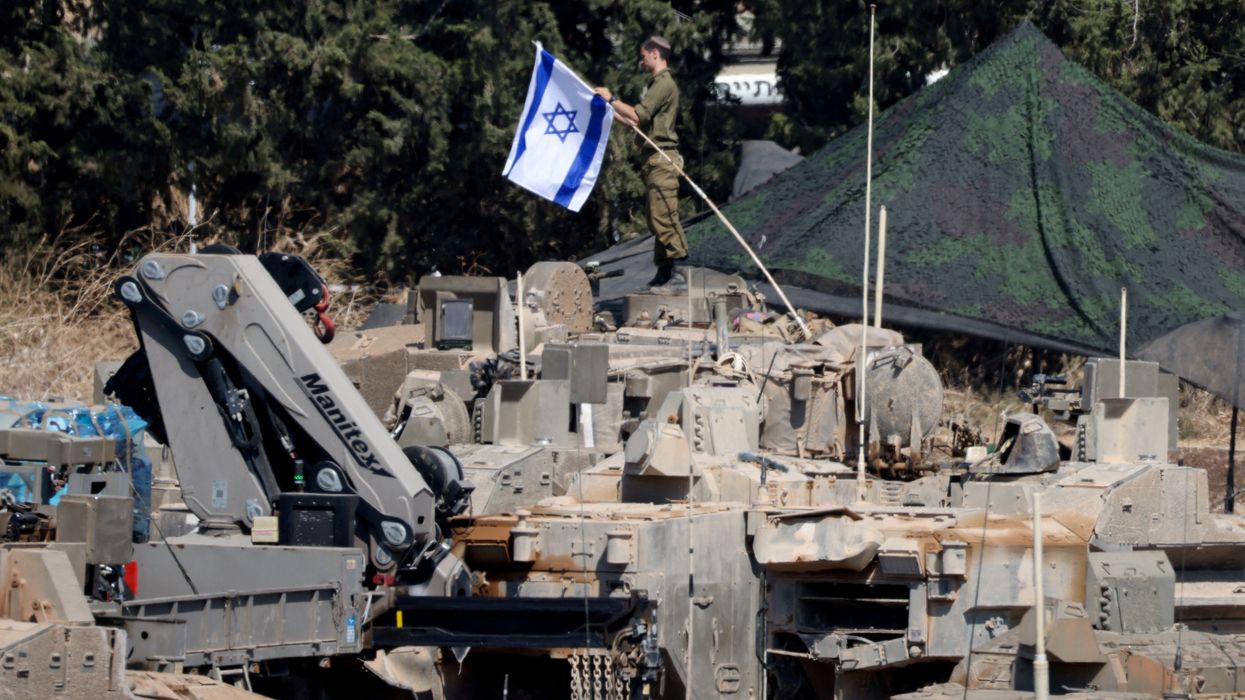 An Israeli member of the military adjusts an Israeli flag as armoured vehicles are arranged in formation, amid cross-border hostilities between Hezbollah and Israel, in northern Israel, September 30, 2024.