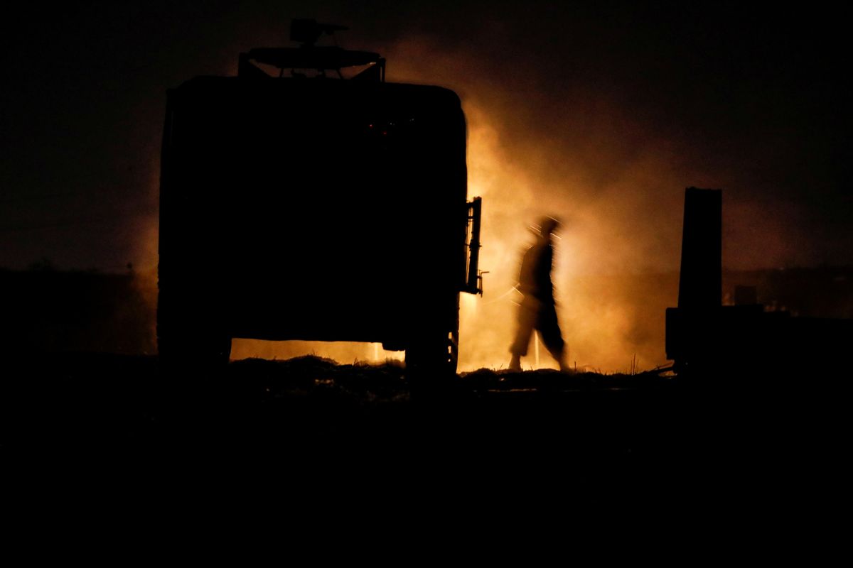 An Israeli soldier walks next to a military vehicle at a mobile artillery unit location on the Israeli side by the Israel border with Gaza May 16, 2021. 