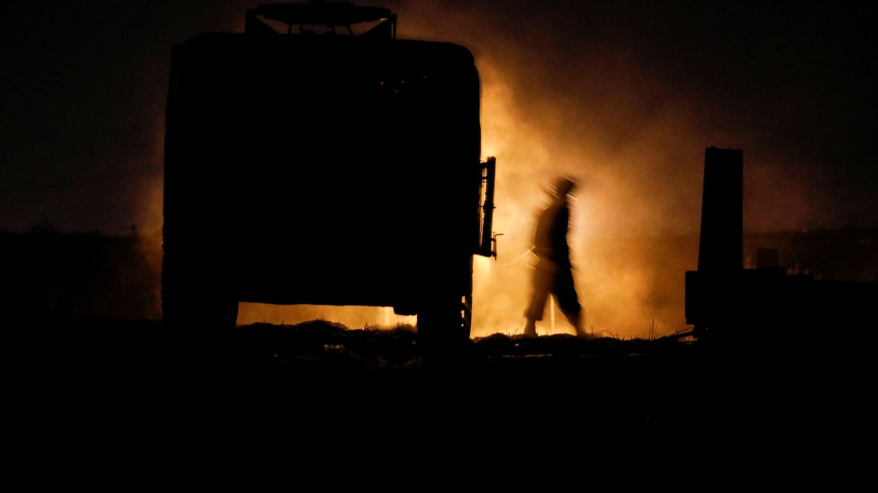 An Israeli soldier walks next to a military vehicle at a mobile artillery unit location on the Israeli side by the Israel border with Gaza May 16, 2021.