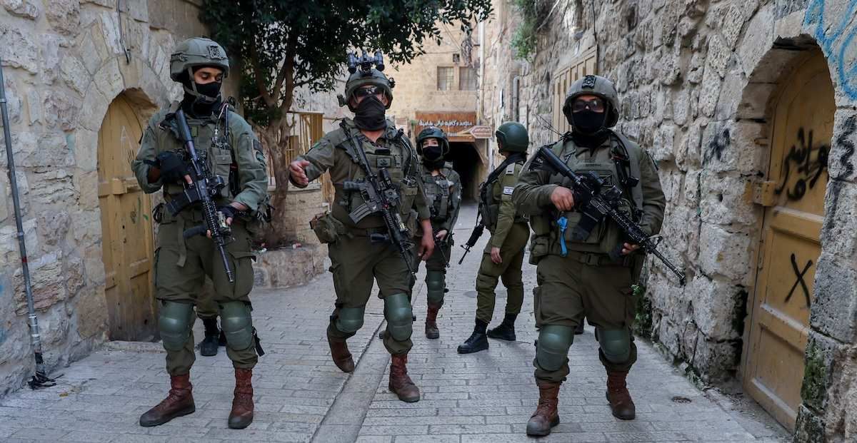 Armed Israeli soldiers walk through an alley in the Old City of Hebron, in the occupied West Bank, on February 7, 2026. The Israeli army routinely secures routes and gathering points when settlers visit the city.