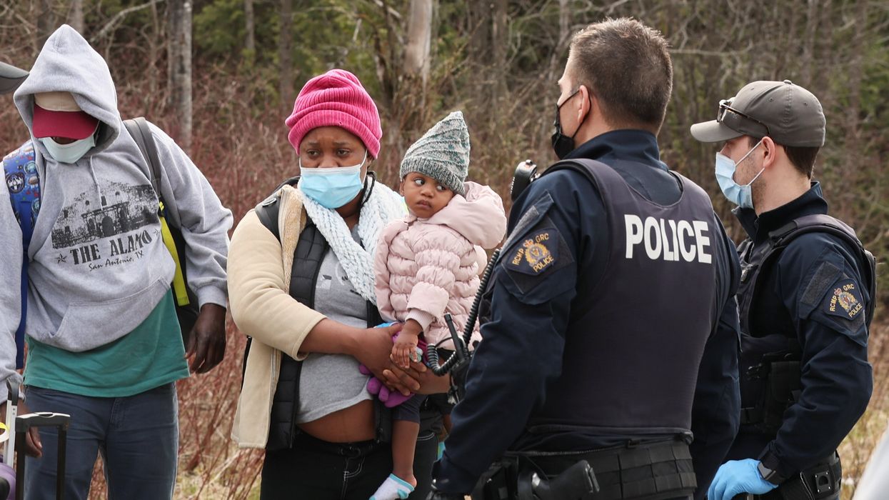 Asylum seekers cross into Canada from the US border near a checkpoint on Roxham Road near Hemmingford, Quebec.