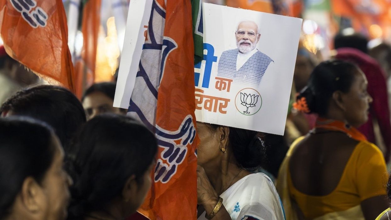 Bharatiya Janata Party supporters hold party flags while waiting for Narendra Modi's road show during an election campaign in Guwahati, Assam, India, on April 16, 2024.