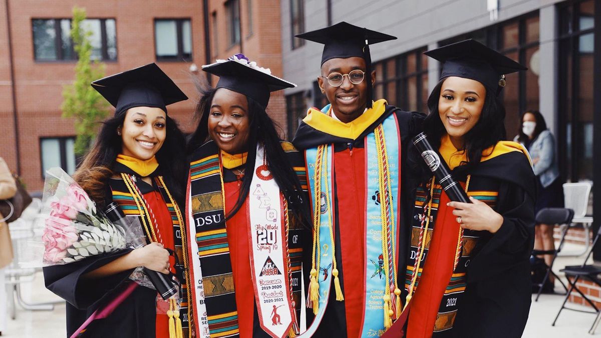 Black college students smiling, dressed in graduation gowns