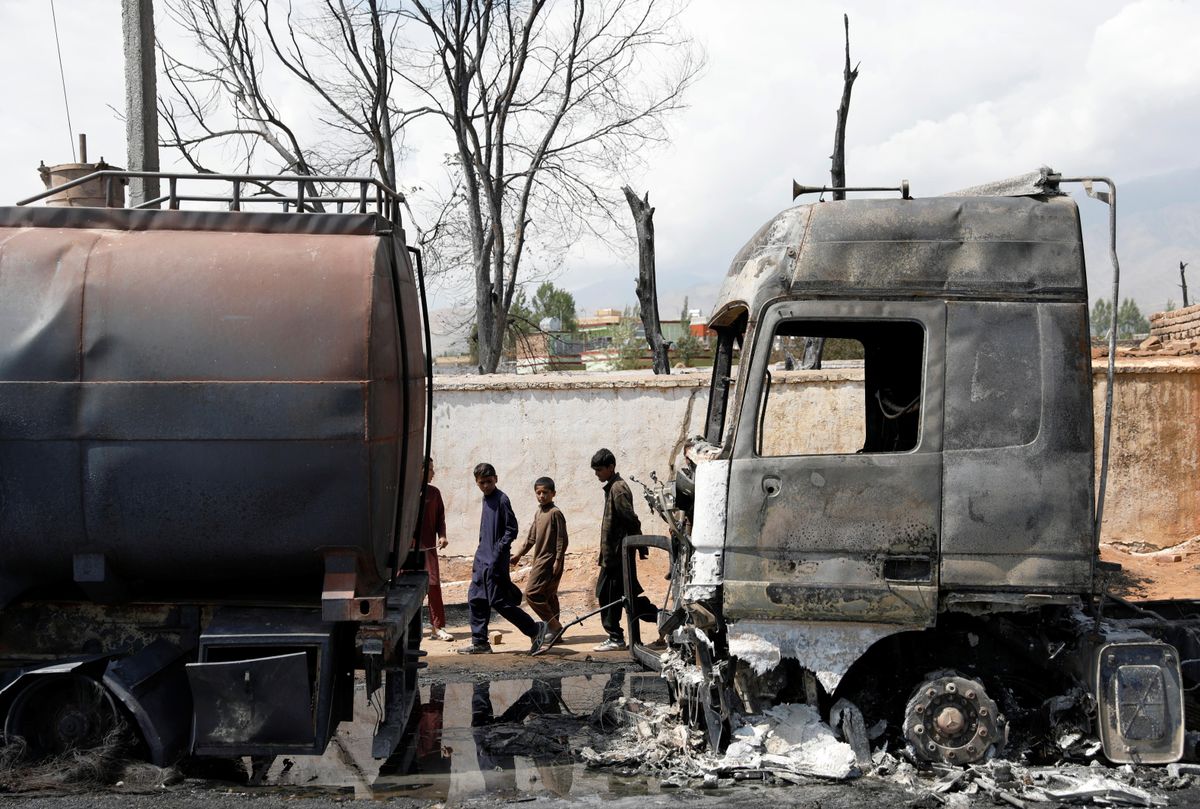 Boys walk past burnt fuel tankers after an overnight fire, on the outskirts of Kabul, Afghanistan May 2, 2021.