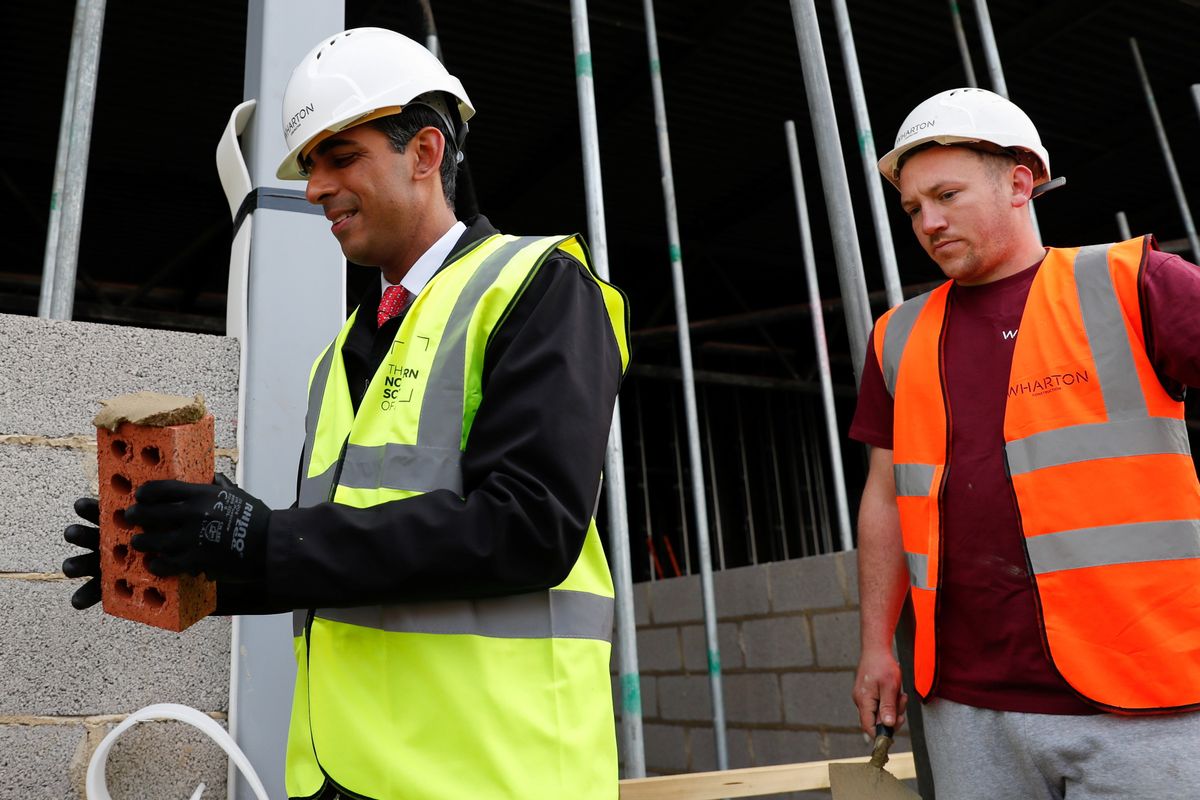 British PM Rishi Sunak holds a brick next to a bricklayer during a local election campaign in Hartlepool when Sunak was chancellor of the exchequer.