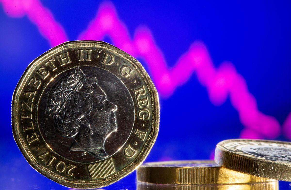 British pound coins are seen in front of displayed stock graph.