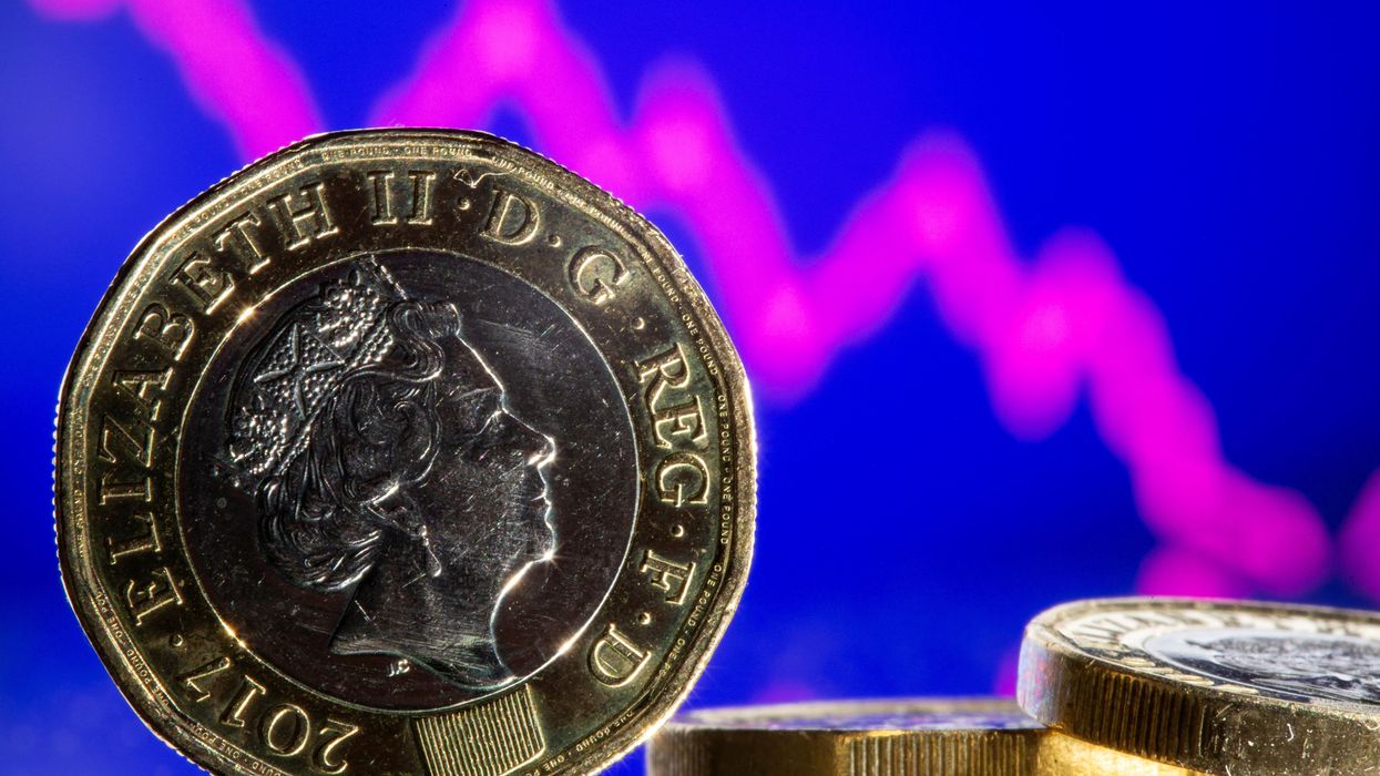British pound coins are seen in front of displayed stock graph.
