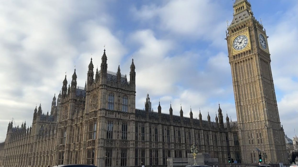 Cabs drive along Westminster Bridge in front of the British Parliament with the Elizabeth Tower and the famous Big Ben bell.