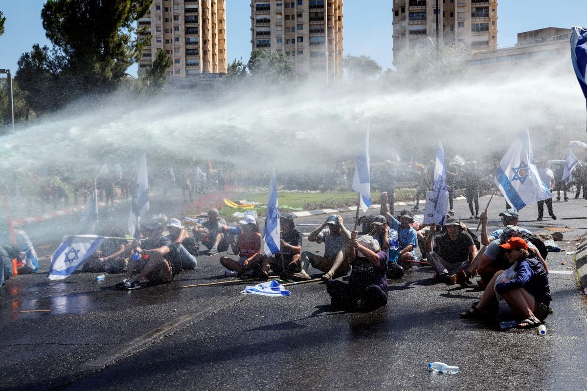 Demonstrators are sprayed with water from a water cannon during a demonstration against the Israeli government's judicial overhaul in Jerusalem