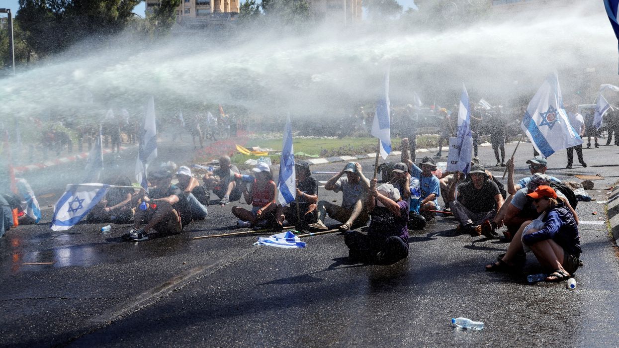 Demonstrators are sprayed with water from a water cannon during a demonstration against the Israeli government's judicial overhaul in Jerusalem