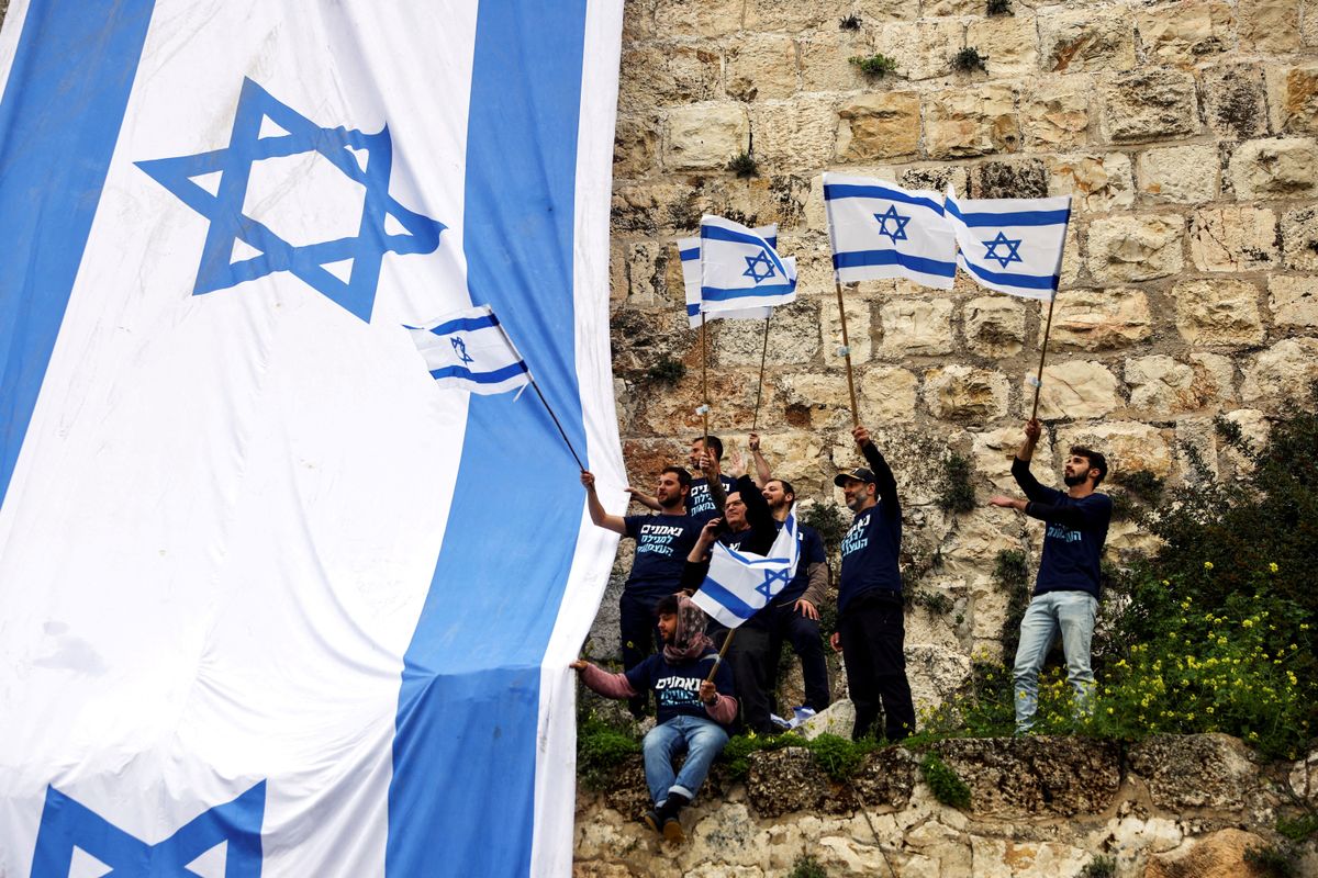 Demonstrators drape the national flag of Israel on the walls of Jerusalem's Old City. 