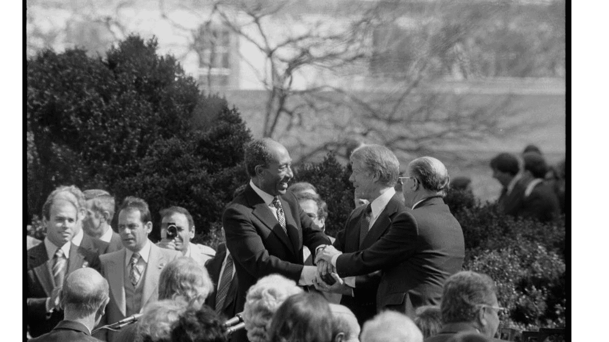 Egyptian President Anwar Sadat and Israeli Prime Minister Menachem Begin shaking hands with US president Jimmy Carter
