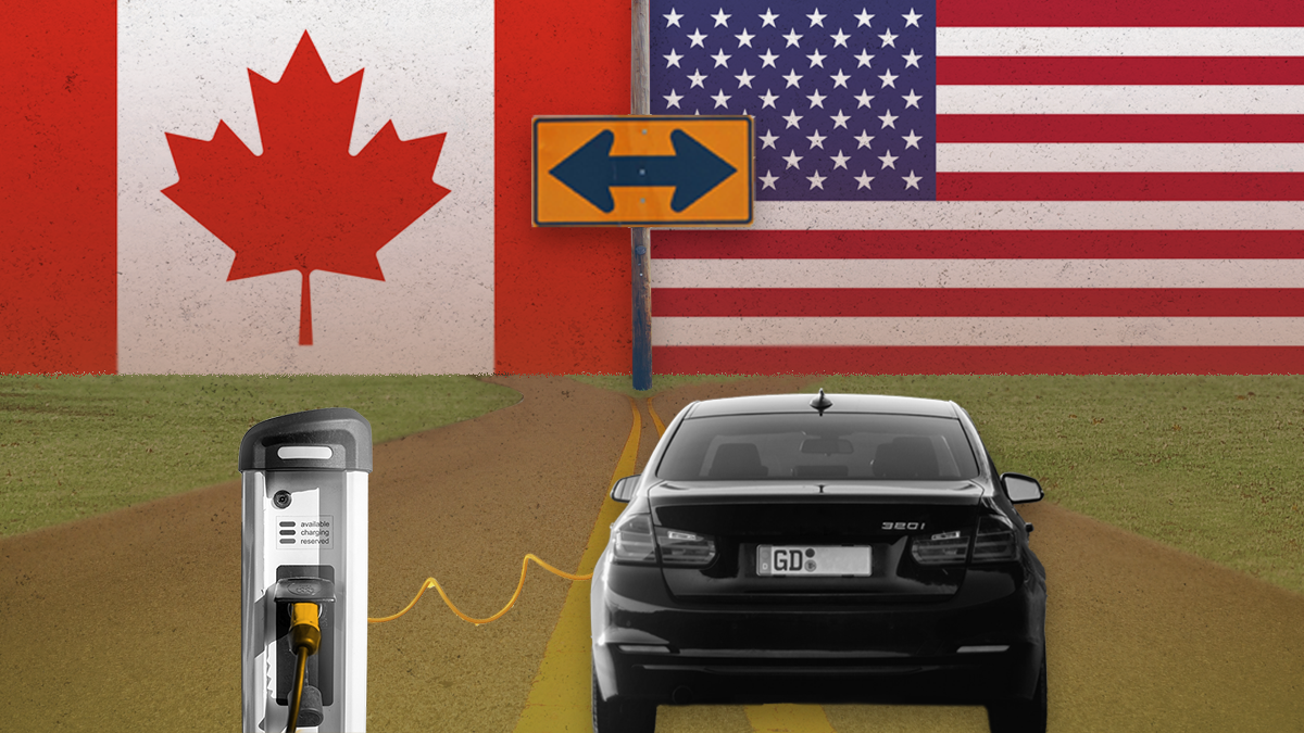 Electric vehicle charging below US and Canada flags with a bifurcation sign