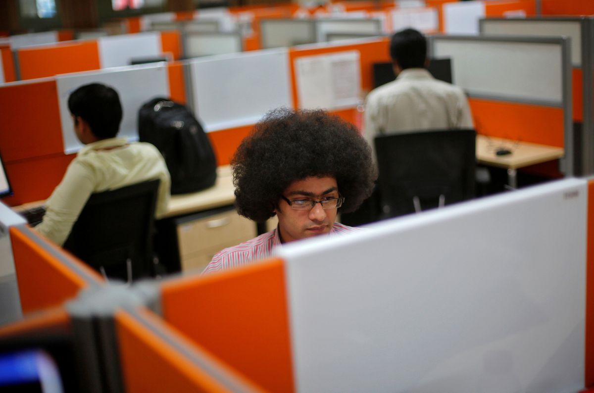 Employees work at their desks inside Tech Mahindra office building in Noida, India. Reuters