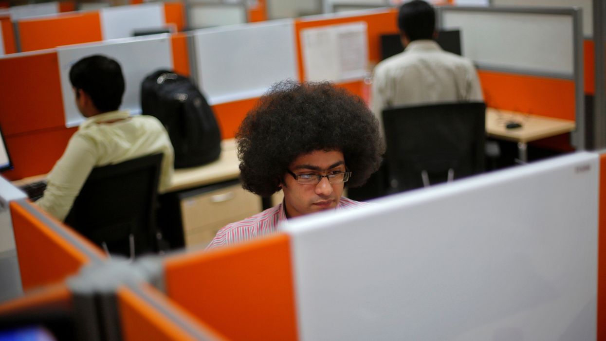 Employees work at their desks inside Tech Mahindra office building in Noida, India. Reuters