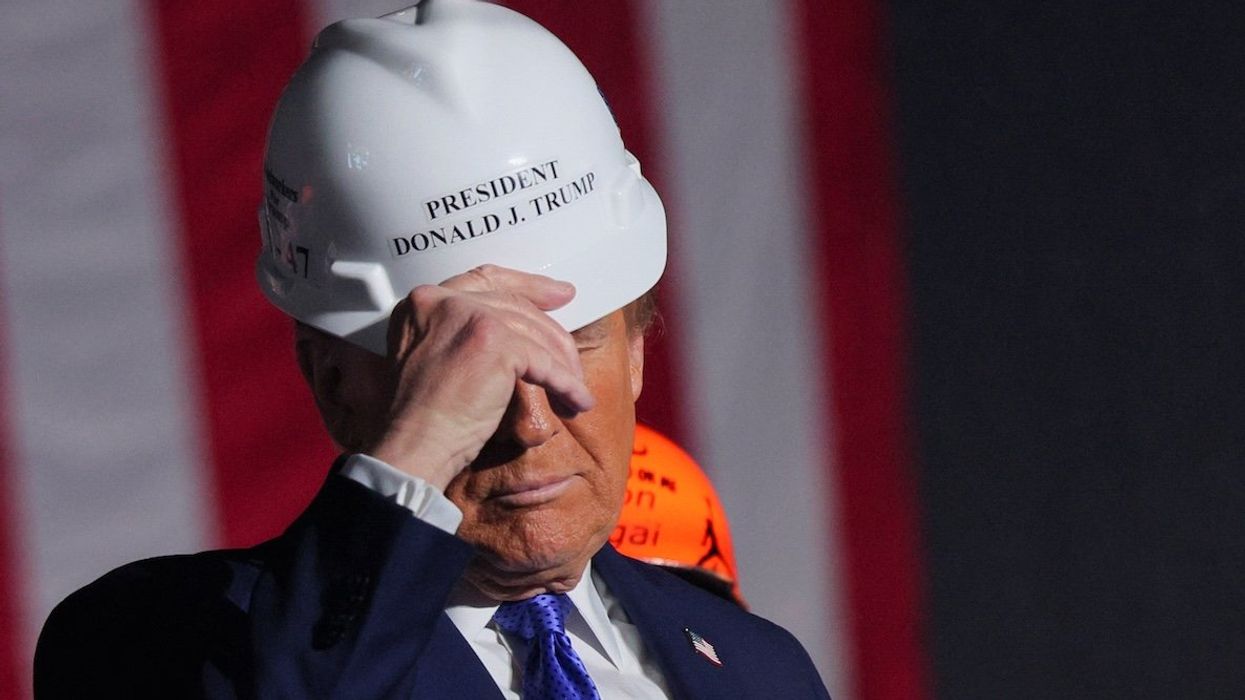 Endorsed by steelworkers onstage, then-Republican presidential nominee Donald Trump puts on a hard hat during his Make America Great Again Rally in Latrobe, Pennsylvania, on Oct. 19, 2024.