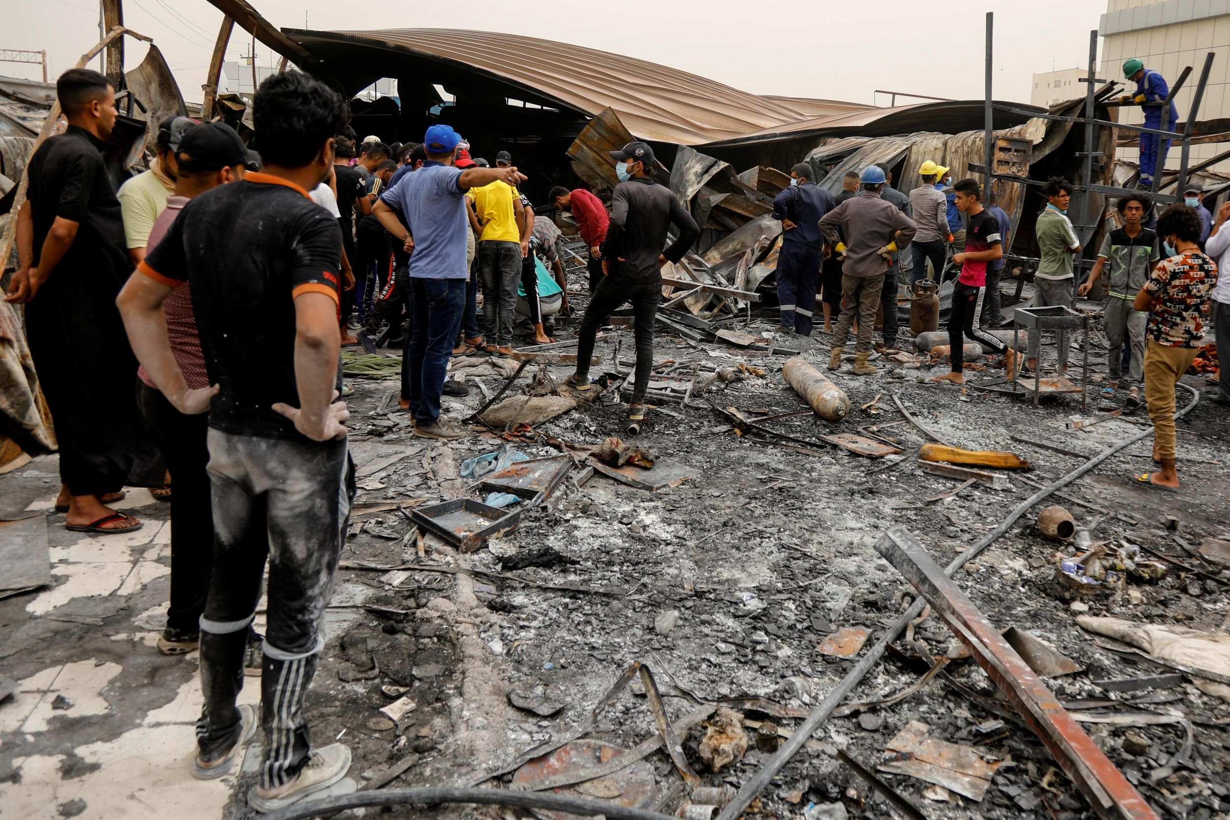 eople gather as they inspect the damage at al-Hussain coronavirus hospital where a fire broke out, in Nassiriya, Iraq, July 13, 2021.
