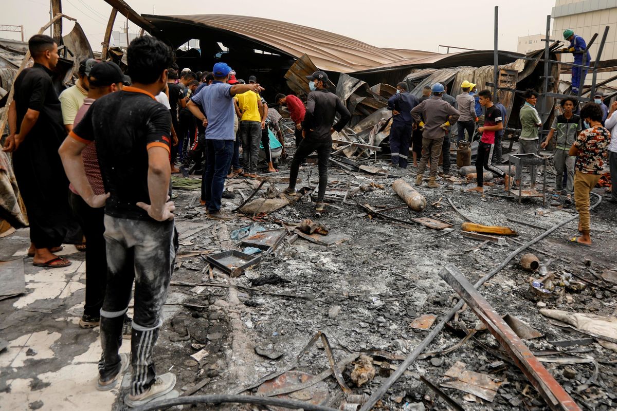eople gather as they inspect the damage at al-Hussain coronavirus hospital where a fire broke out, in Nassiriya, Iraq, July 13, 2021. 