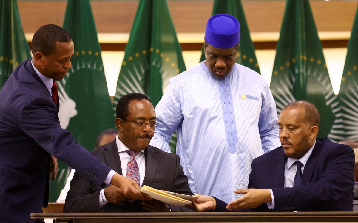 Ethiopian government representative Redwan Hussien and Tigray delegate Getachew Reda pass documents during the signing of the AU-led negotiations to resolve the conflict in northern Ethiopia