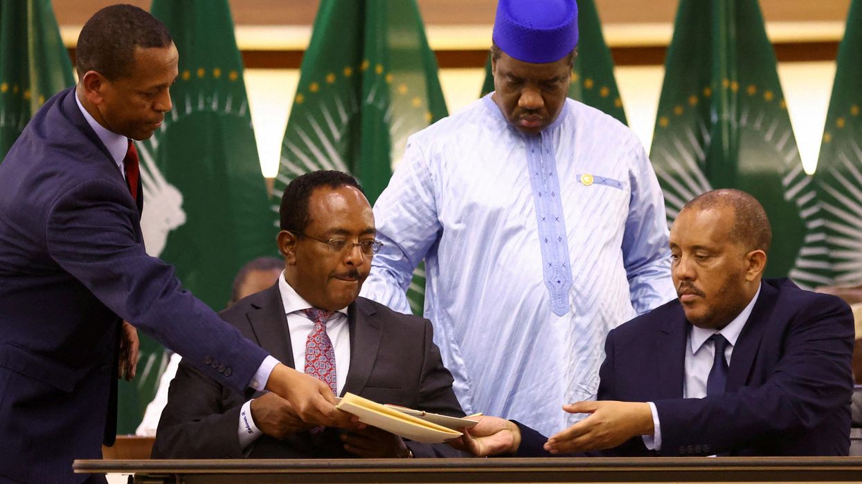 Ethiopian government representative Redwan Hussien and Tigray delegate Getachew Reda pass documents during the signing of the AU-led negotiations to resolve the conflict in northern Ethiopia